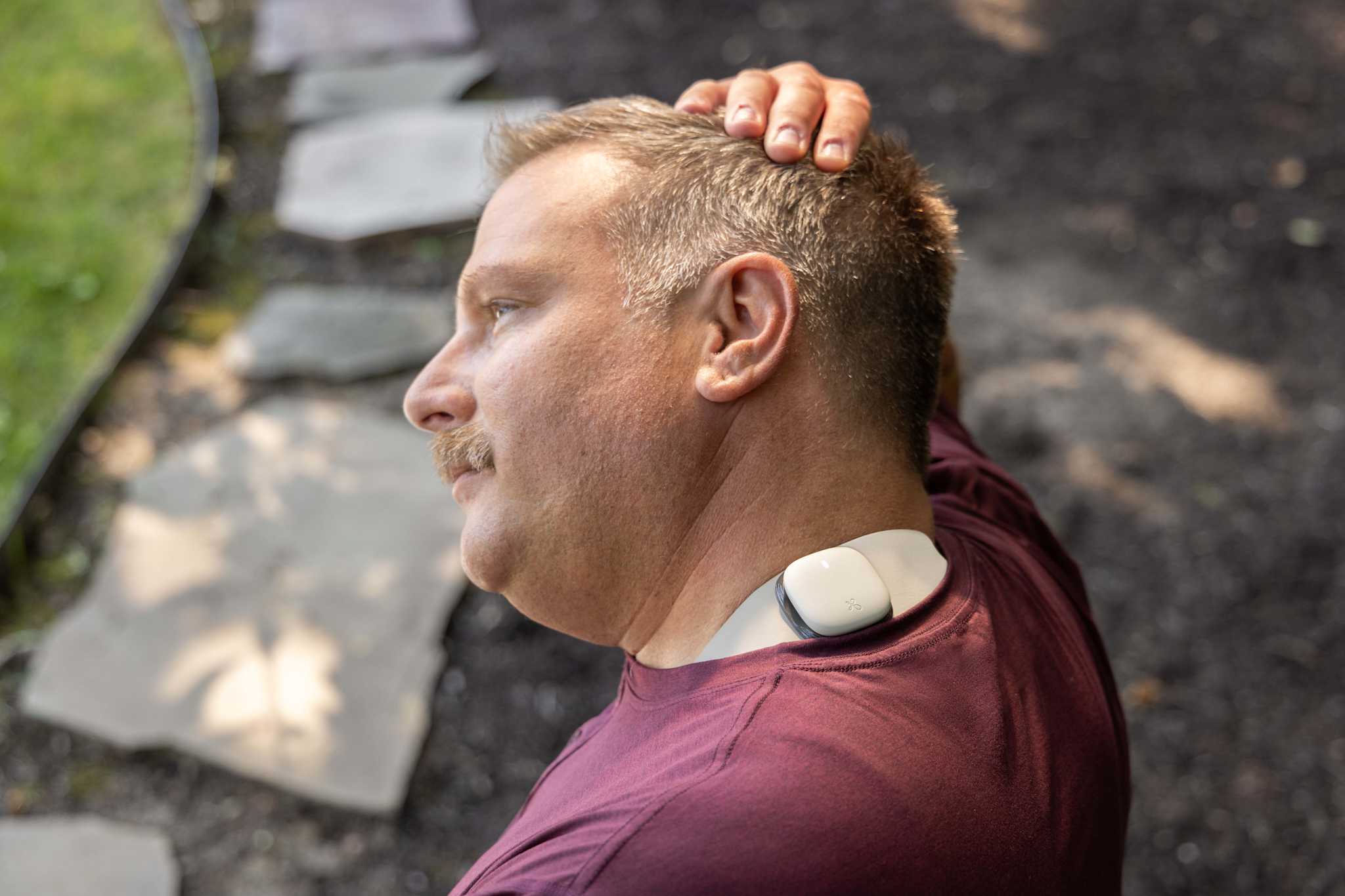 Image of a man performing a neck stretch with his hand on his head and Enso attached to the side of his neck
