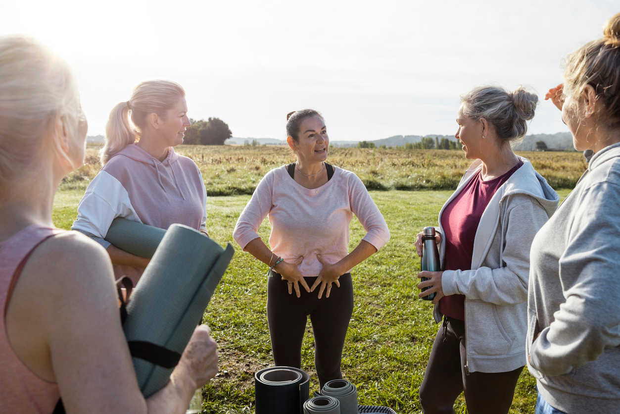 groups-of-woman-doing-yoga-outdoors-on-field-touching-their-pelvis