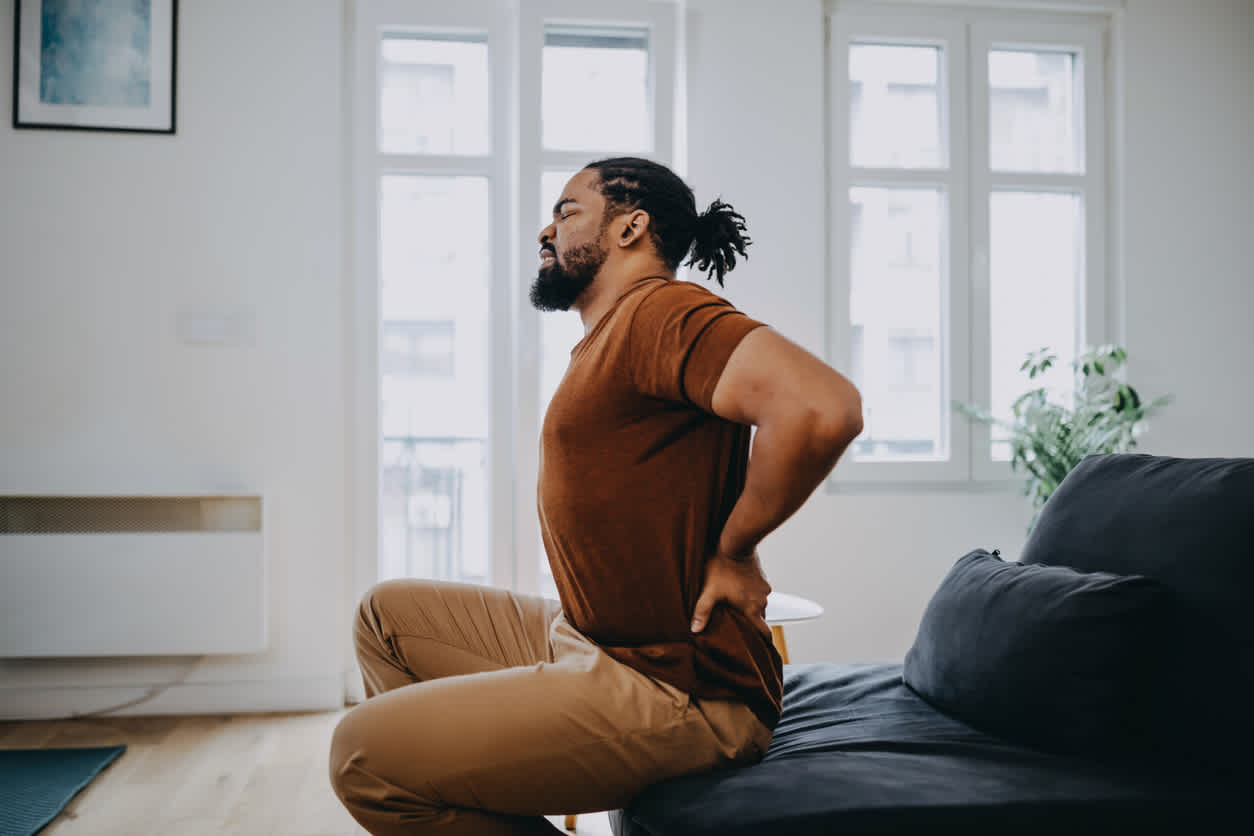 man-sitting-at-home-holding-lower-back-in-pain