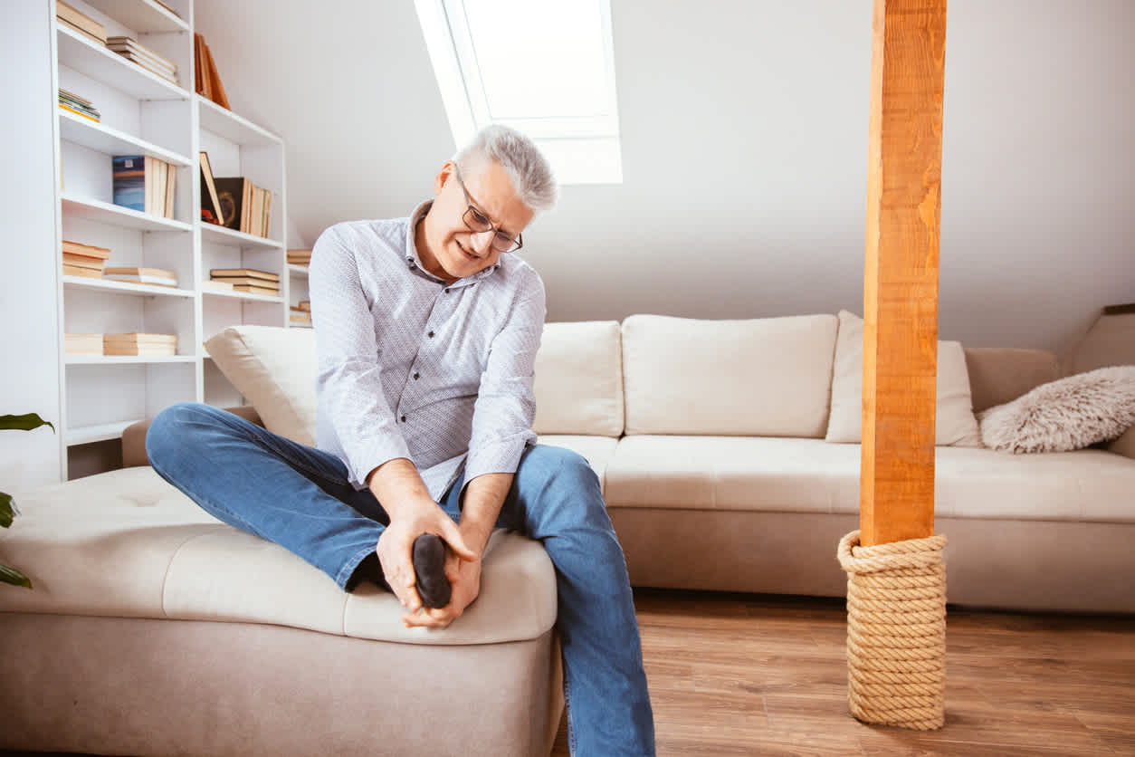 man-touching-his-feet-and-ankles-in-pain-sitting-at-home