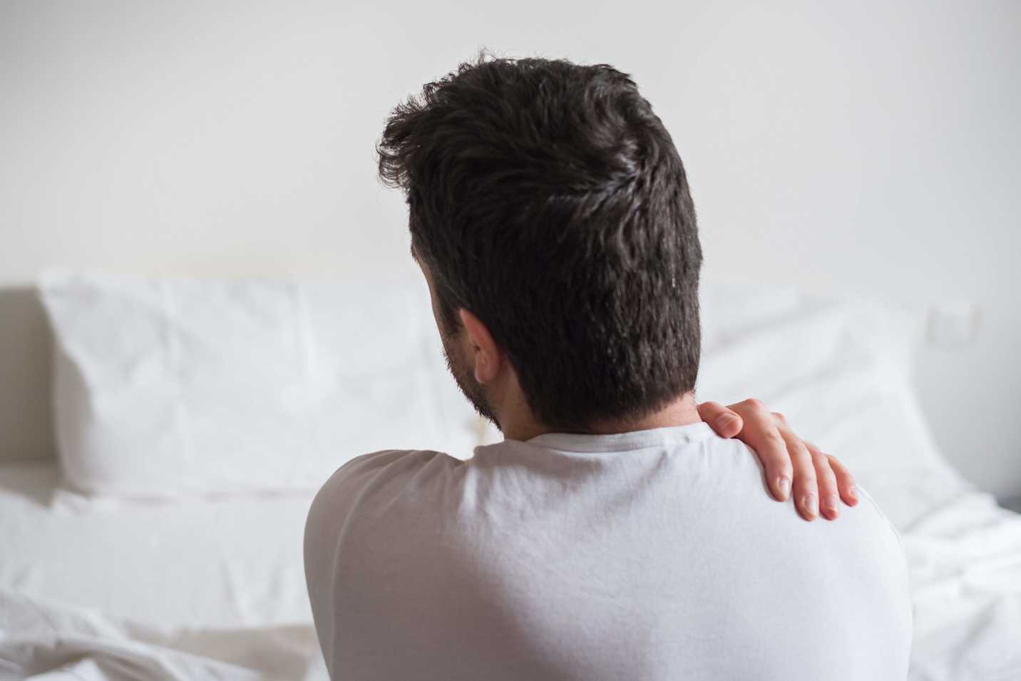 Photo of a man robbing his shoulder with his left hand