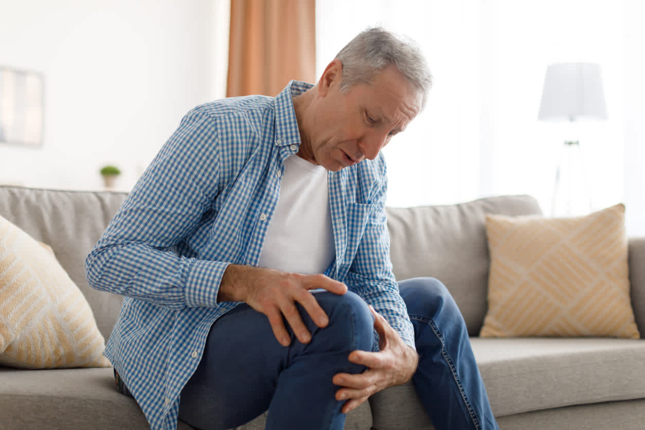 old-man-holding-his-knee-on-a-couch