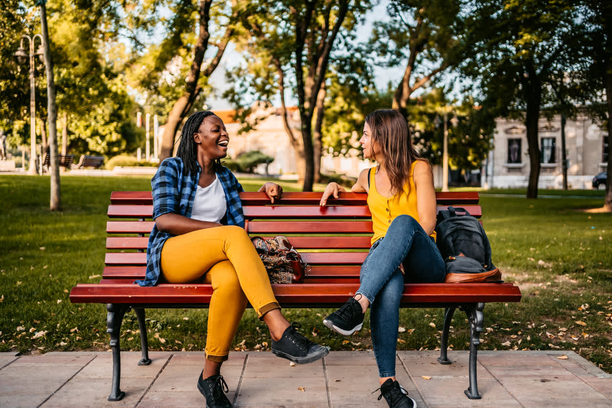Two-women-sitting-with-legs-crossed-on-park-bench