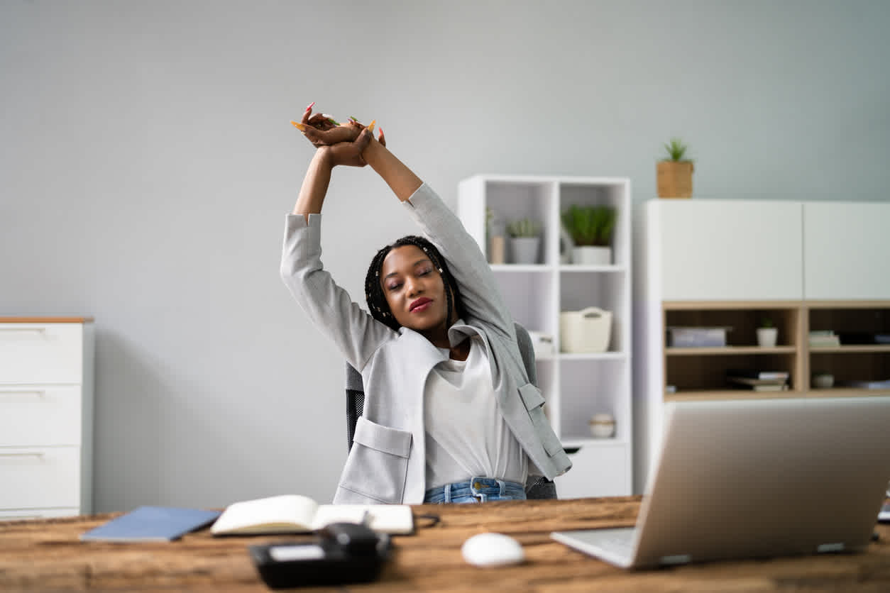 Woman-stretching-her-arms-and-back-while-sitting-at-her-desk