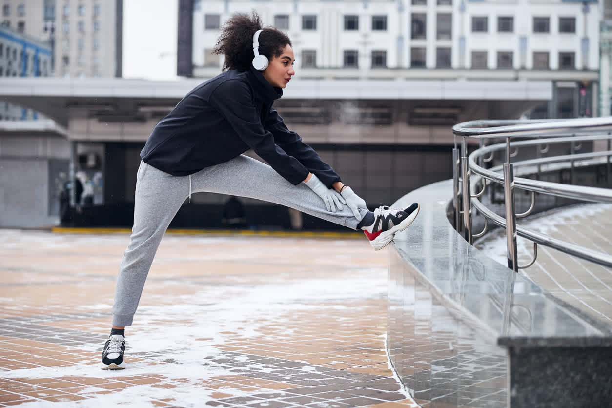 Woman-with-headphones-stretching-legs-before-outdoor-run