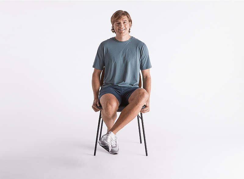 Man-smiling-sitting-on-a-chair-doing-external-hip-rotations