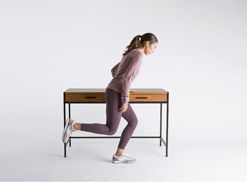 Woman-doing-a-slingle-leg-squat-holding-onto-table