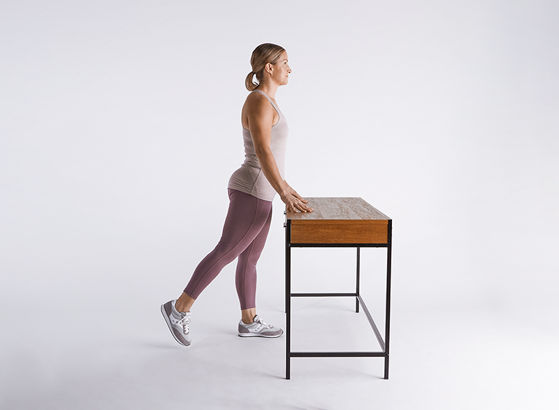 woman-standing-in-front-of-desk-with-leg-extended